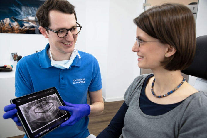 Franz Eschlberger, Zahnarzt in Augsburg, zeigt einer Patientin den Scanner Ihrer Zähne